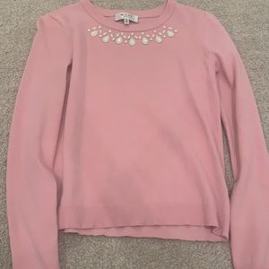 This is a pink sweater with a detailed neck line